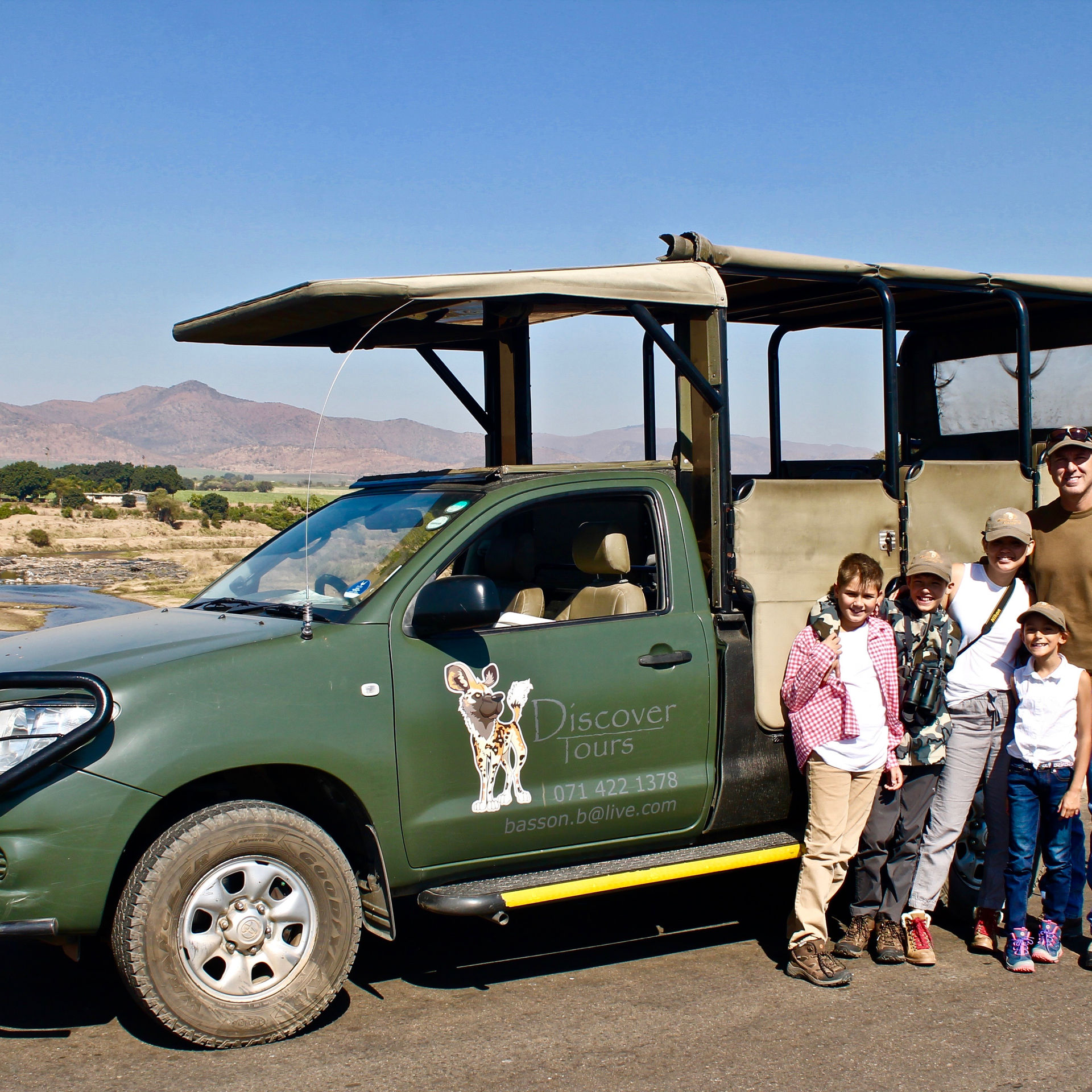 Family with the safari vehicle on a river road